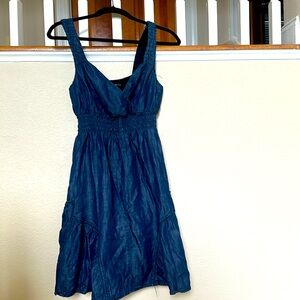 Ruffled sleeveless deep blue denim dress with side pockets.